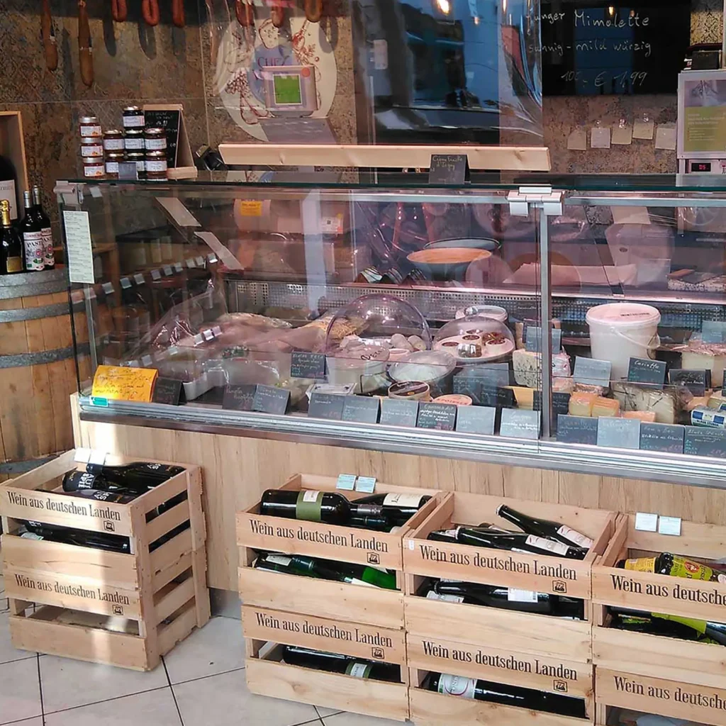Chez Martin Ihre Käse- & Weintheke in Potsdam-Babelsberg. Käsesortiment in Käsetheke mit Weinkisten aus Holz davor