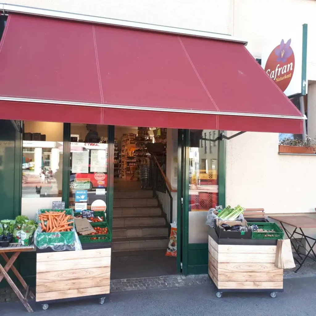 Safran Naturkost Ihr Bioladen mit Charme. Mehr als BIO. - Außenansicht mit Obst- und Gemüsekisten vor dem Schaufenster
