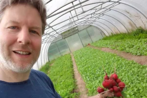 Safran Naturkost Ihr Bioladen mit Charme. Herr Sylvain Durand Inhaber und Geschäftsführer mit frisch geernteten Radieschen in der Hand in einem großen Gewächshaus